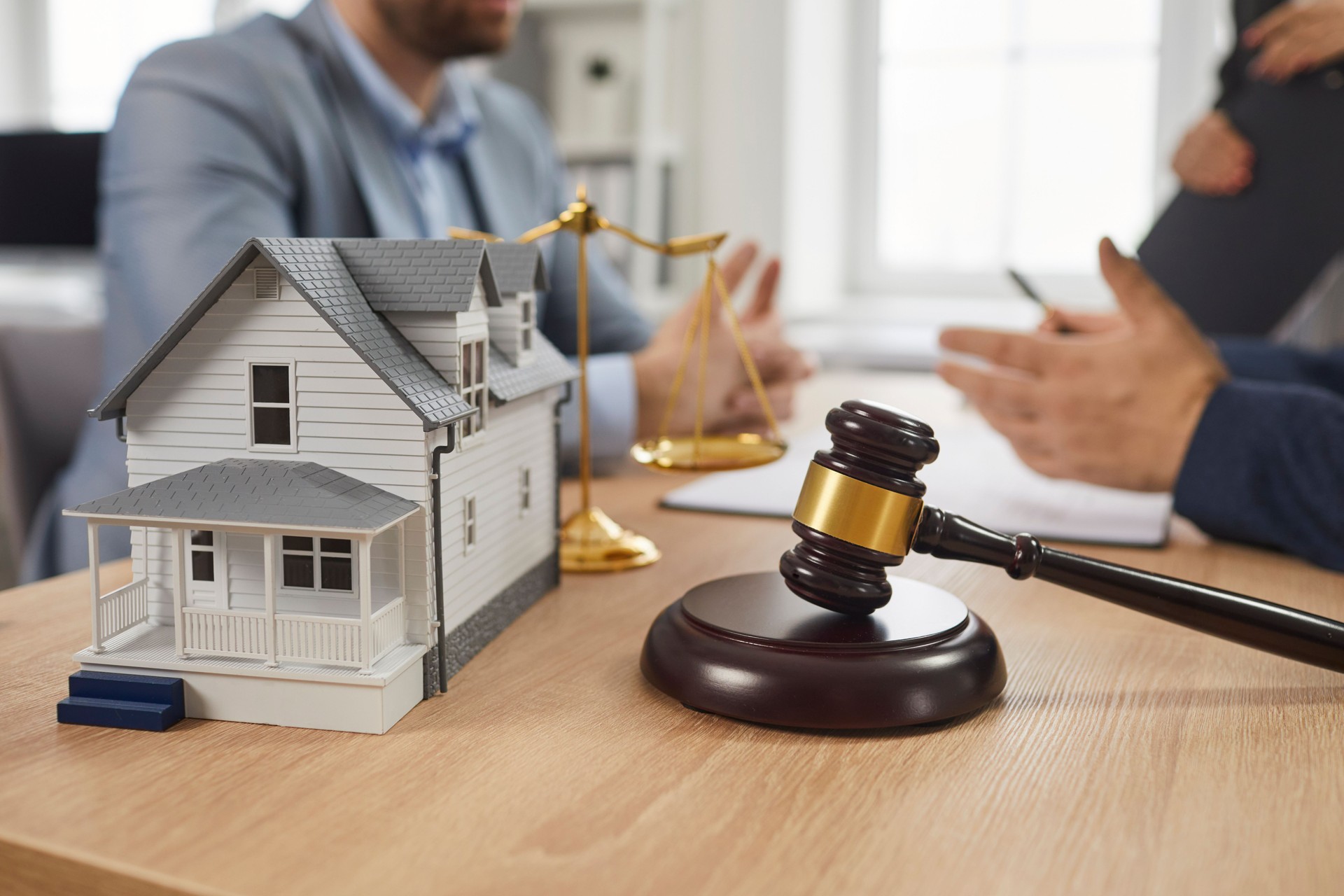 People having consultation with property lawyer at table with gavel and house model